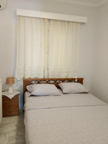 a bedroom with two beds and a window with white curtains at beach mourteri Evia in Mourteri
