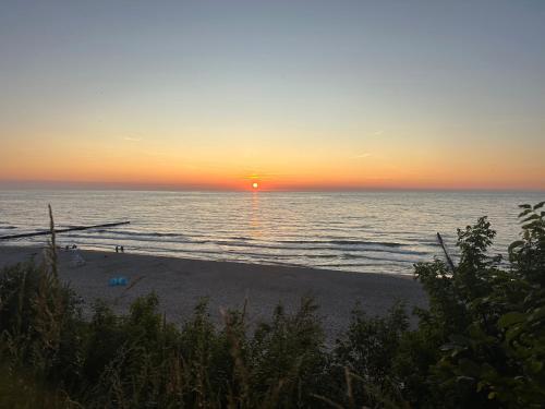 a sunset on a beach with the ocean at Villa Hoff Wellness & Spa in Trzęsacz