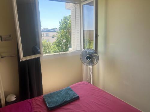 a bedroom with a pink bed and a window at Calme et écologie aux portes de Paris in Ivry-sur-Seine