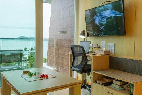 an office with a desk and a chair and a television at C114 Romantic Getaway Seaview, Pool, Gym Access in Ban Saiyuan (1)