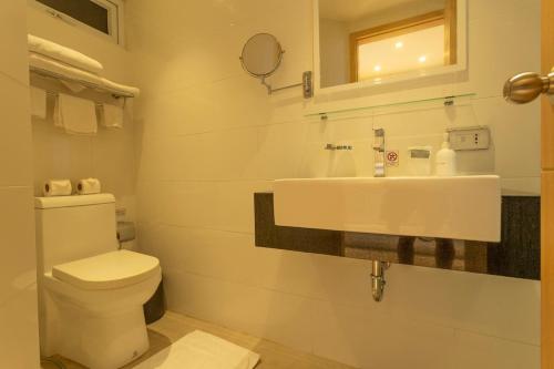 a white bathroom with a toilet and a sink at C114 Romantic Getaway Seaview, Pool, Gym Access in Ban Saiyuan (1)