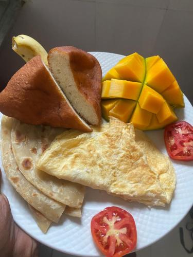 a plate of breakfast food with eggs bread and fruit at Reef 2Nungwi House in Nungwi