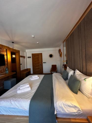 a large bed with two towels on top of it at Forest Green & Spa in Gura Humorului