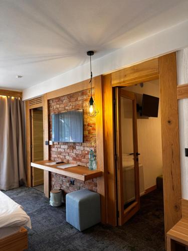 a hotel room with a desk and a brick wall at Forest Green & Spa in Gura Humorului