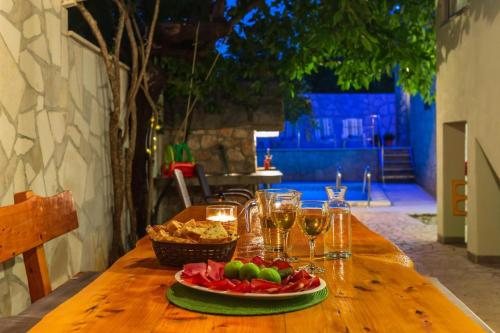 a table with a plate of fruit and wine glasses at MSV Modern Stone Villa in Imotski