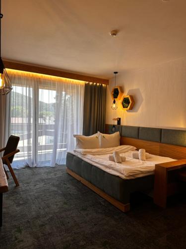a bedroom with a large bed and a large window at Forest Green & Spa in Gura Humorului