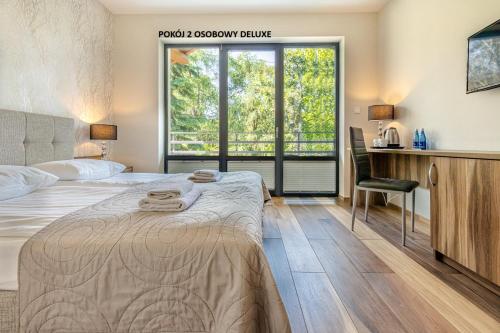 a bedroom with a bed and a desk and a window at Villa Pacyfic in Krynica Morska