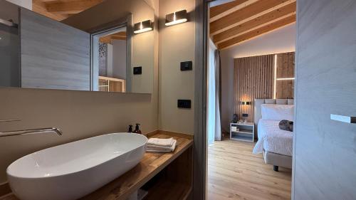a bathroom with a white tub and a bedroom at A&F LUXURY Rooms Pinzolo in Pinzolo