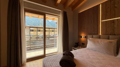 a bedroom with a bed and a large window at A&F LUXURY Rooms Pinzolo in Pinzolo