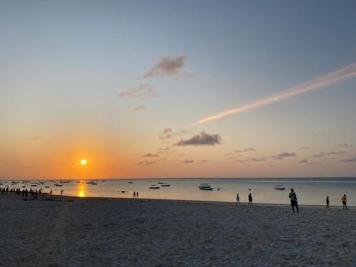 a group of people on the beach at sunset at Reef 2Nungwi House in Nungwi