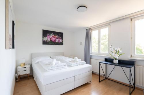 a white bedroom with a bed and a table at Charmante Fohnsdorfer-Wohnung in Red Bull Ring Nähe in Fohnsdorf
