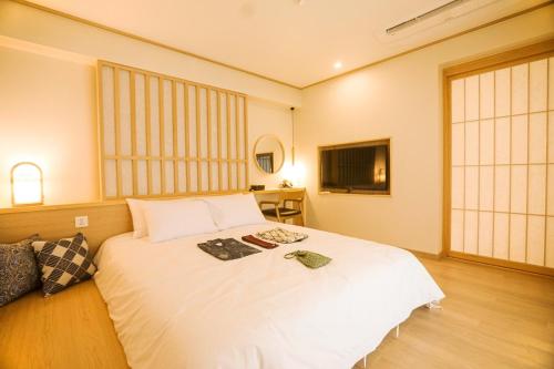 南海郡Tomonoya Signature Ryokan Namhae的卧室里有一张白色的大床和一台电视