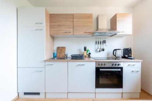 a kitchen with white cabinets and a stove at Charmante Fohnsdorfer-Wohnung in Red Bull Ring Nähe in Fohnsdorf