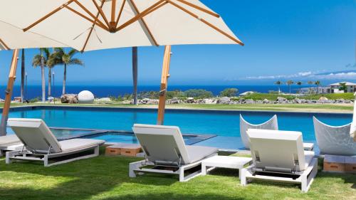 a group of chairs and umbrellas next to a swimming pool at MAUNA KEA BEACH ESCAPE Luxurious home in private community with Heated Private Pool and Spa Detached Ohana Suite in Waimea