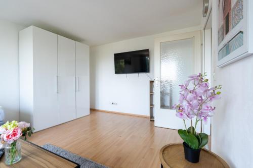a living room with white cabinets and a table with purple flowers at Charmante Fohnsdorfer-Wohnung in Red Bull Ring Nähe in Fohnsdorf