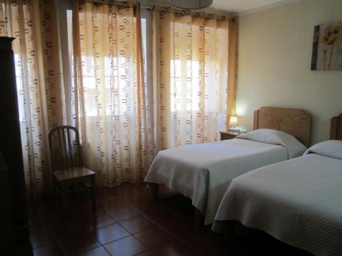 Un dormitorio con dos camas y una ventana con cortinas. en Apartamentos Valdemar, en Viana do Castelo