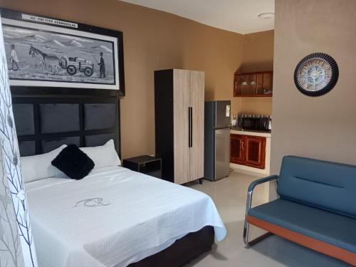 a bedroom with a white bed and a blue chair at MC One Stop Road Lounge Hotel in Xai-Xai