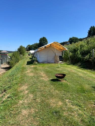 a field with a tent and a grill in the grass at Comfort tent Val de Wanne in Trois-Ponts