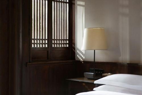 a bedroom with a bed and a lamp and a window at Lijiang Old Town Anyu hotel in Lijiang
