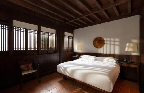 a bedroom with a large white bed and a chair at Lijiang Old Town Anyu hotel in Lijiang