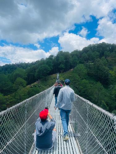 a group of people walking on a suspension bridge at Nagarkot New Homestay in Nagarkot