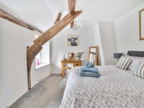 a white bedroom with a bed and a table at 2 Pigsfoot Cottages in Tiverton