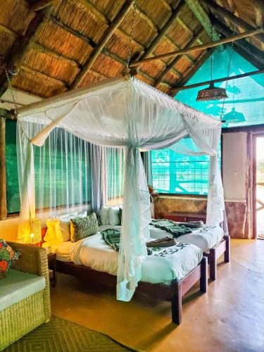 a bedroom with two beds and a canopy at Thornicroft Lodge - South Luangwa in Mpanda