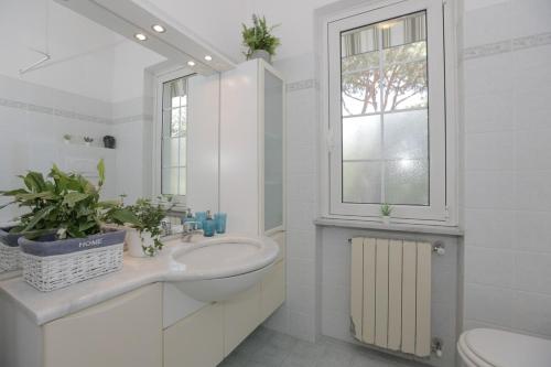 Un baño con lavabo, inodoro y ventana. en FORTE DEI MARMI - 500m to the sea, en Marina di Massa