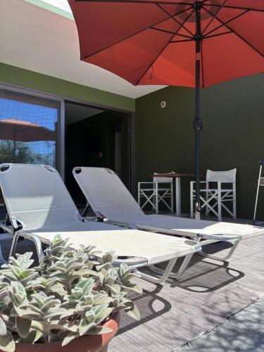 two lounge chairs and an umbrella on a patio at FinIQ Boutiq Studios in Foiníki