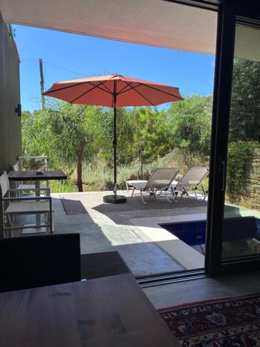 a patio with a table and an umbrella and chairs at FinIQ Boutiq Studios in Foiníki