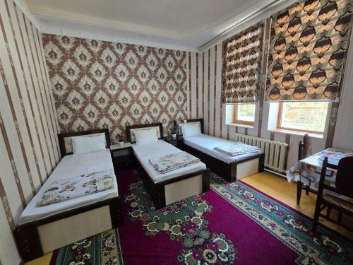 una habitación con dos camas y una alfombra en Sezam, en Bukhara