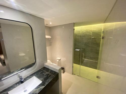 a bathroom with a mirror and a sink and a shower at Grand Whiz Hotel Praxis Surabaya in Surabaya