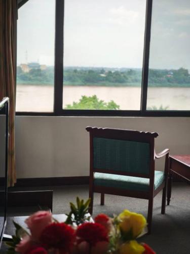 a room with a table and a chair and a window at Royal Mekong Riverside Hotel in Nong Khai