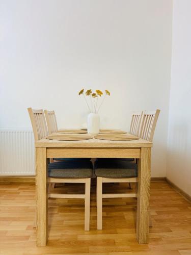 a wooden table with two chairs and a vase with flowers at V srdci mesta II in Stará Turá