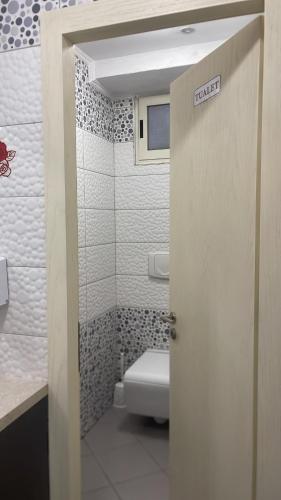 a bathroom with a toilet and a door with a sign at Jacuzzi Escape in Tirana