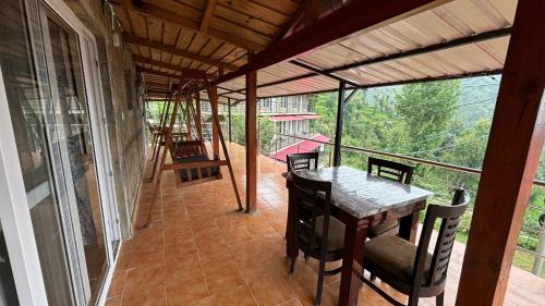 a screened in porch with a table and chairs at Indus Valley Homestay in Mukteswar