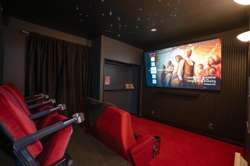 a cinema room with red chairs and a flat screen tv at Free Parking -Kids Games Room w PS5, Arcade- Central-7 Bathrooms- Cinema in Christchurch