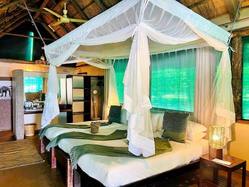 a bedroom with two beds with a canopy at Thornicroft Lodge - South Luangwa in Mpanda
