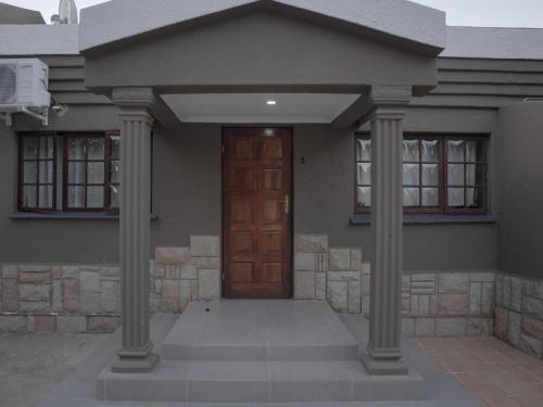 a house with two columns and a wooden door at Insolam Accommodation in Mokopane