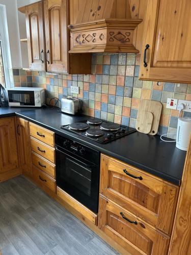 a kitchen with a black stove and wooden cabinets at 3 Bedroom Family home in Limavady