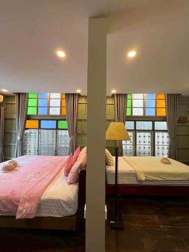 two beds in a room with a stained glass window at tamarind guesthouse in Phra Nakhon Si Ayutthaya