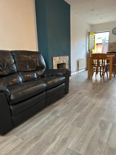 a black leather couch in a living room with a fireplace at 3 Bedroom Family home in Limavady