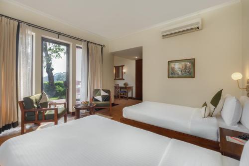 a hotel room with two beds and a window at Gokarna Forest Resort Kathmandu in Kathmandu