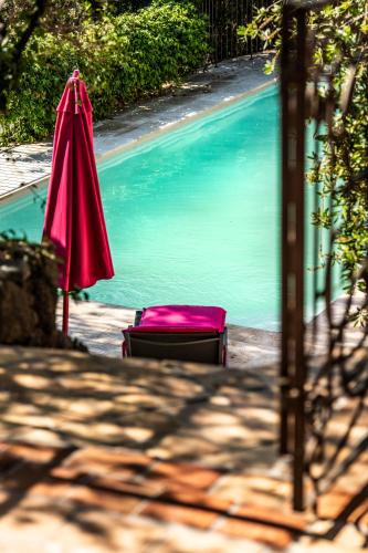 a red umbrella and a chair next to a swimming pool at A Melingrana in Lecci