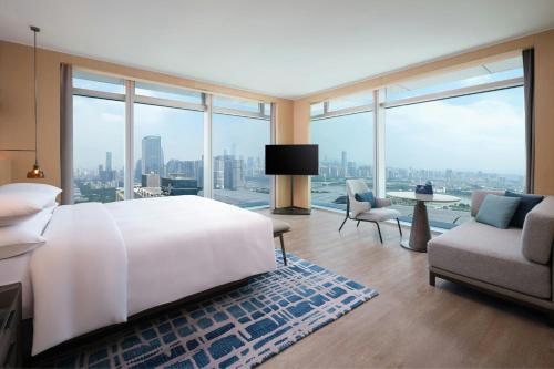 a bedroom with a large white bed and a large window at Courtyard by Marriott Guangzhou Pazhou in Guangzhou