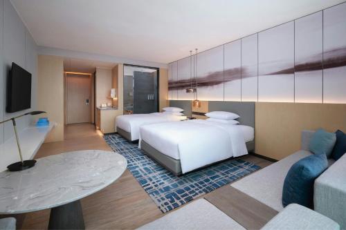 a hotel room with two beds and a couch at Courtyard by Marriott Guangzhou Pazhou in Guangzhou