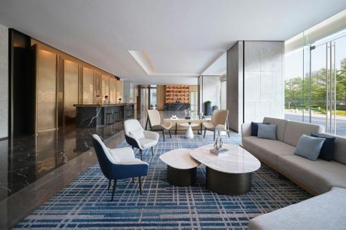 a living room with a couch and a table and chairs at Courtyard by Marriott Guangzhou Pazhou in Guangzhou