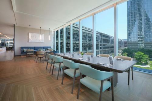 a long table and chairs in a room with large windows at Courtyard by Marriott Guangzhou Pazhou in Guangzhou