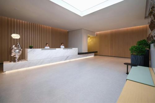 a lobby with two people standing at a reception desk at Courtyard by Marriott Guangzhou Pazhou in Guangzhou