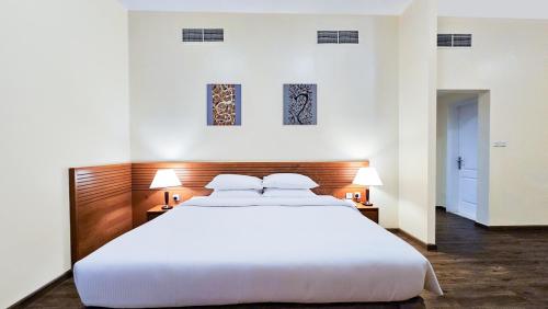a large white bed in a room with two lamps at Ramada Hotel & Suites by Wyndham Ajman in Ajman 